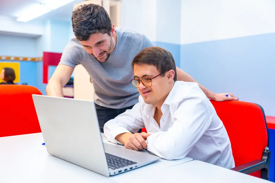 Young man with Down syndrome using his computer with his support worker
