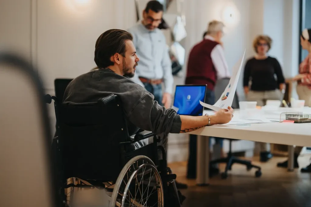 Young male professional in wheelchair in an office setting looking at paperwork