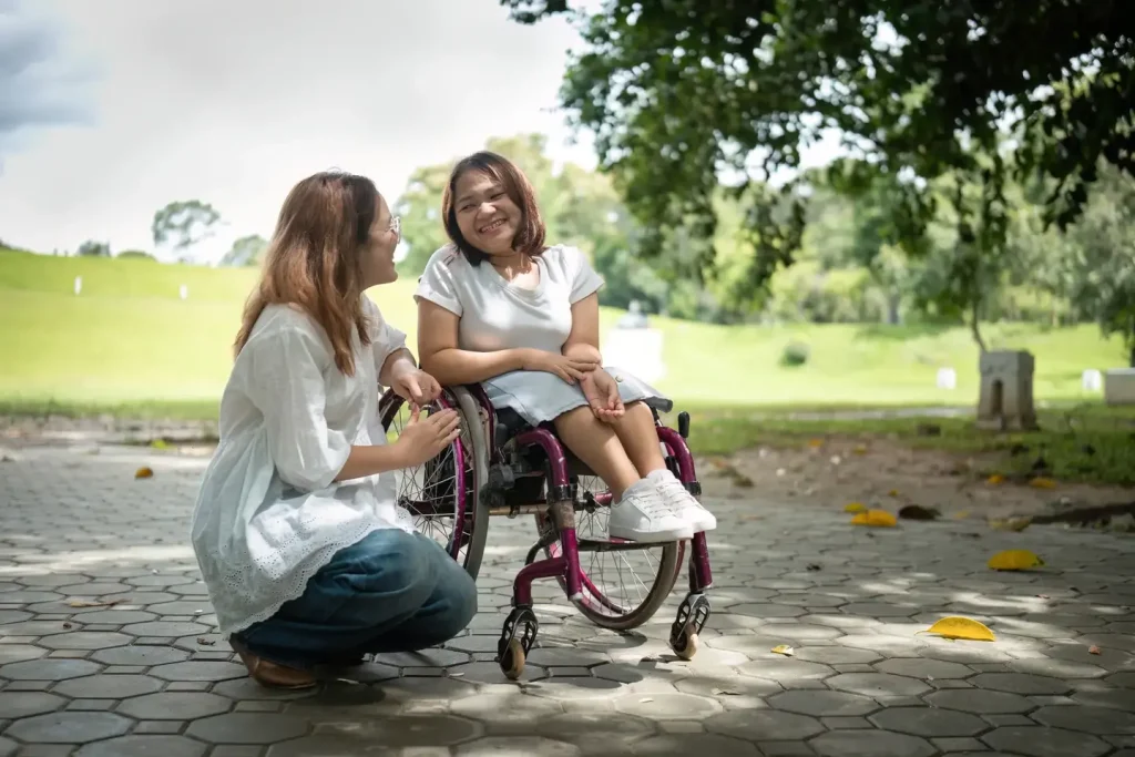 Woman in wheelchair smiling and having a conversation with her female support worker