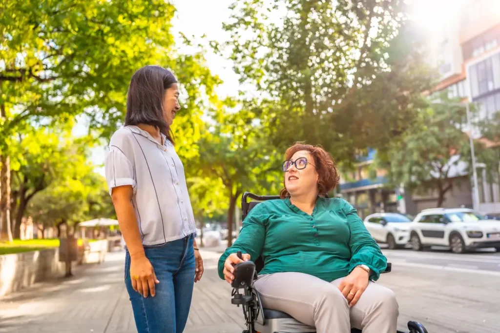 Woman in wheelchair outside with her female support worker - they are enjoying a conversation