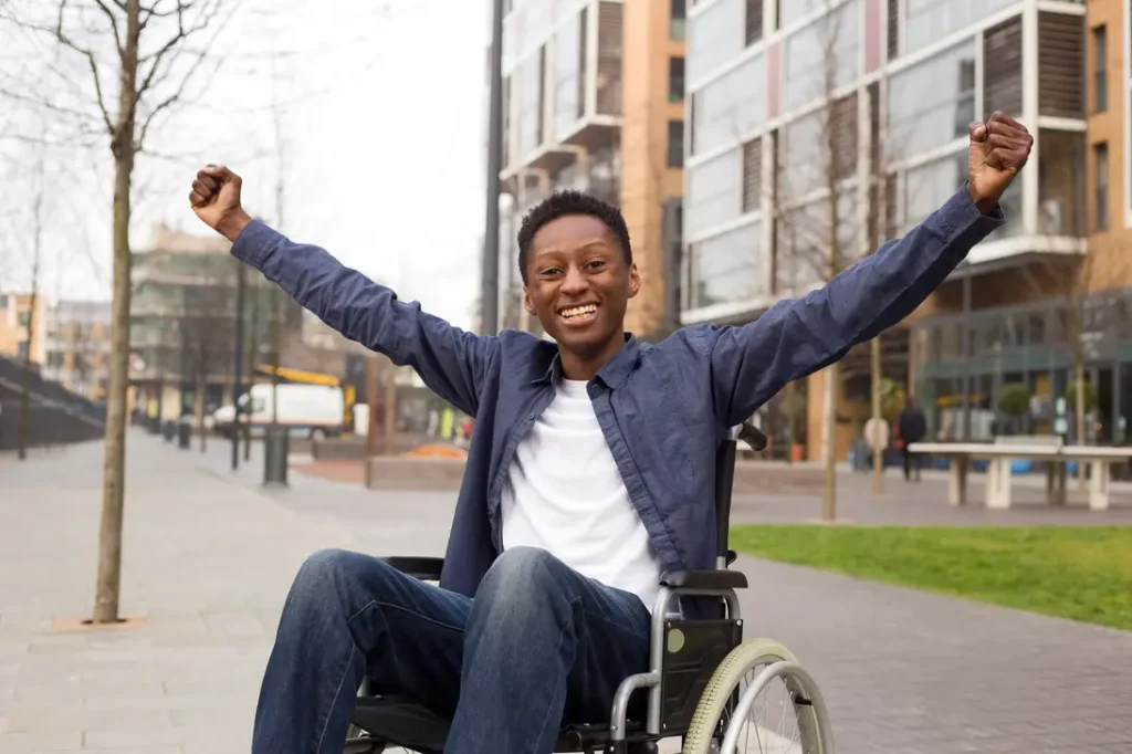 Young disabled man in a wheelchair waving his hands in the air with joy