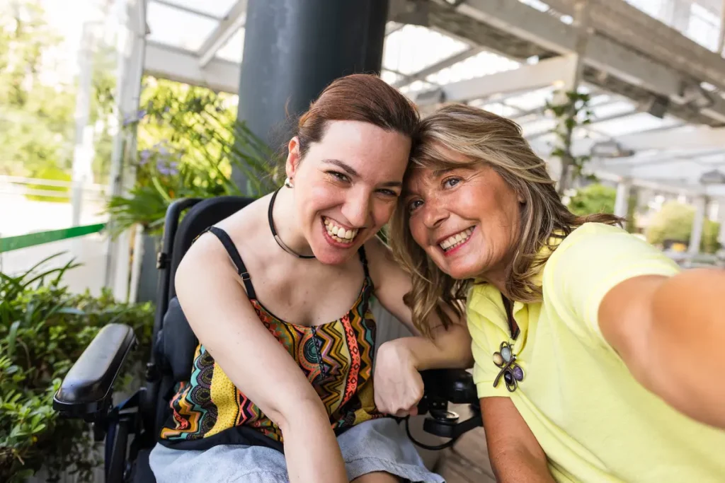 Woman in wheelchair and her support worker smiling confidently at the camera