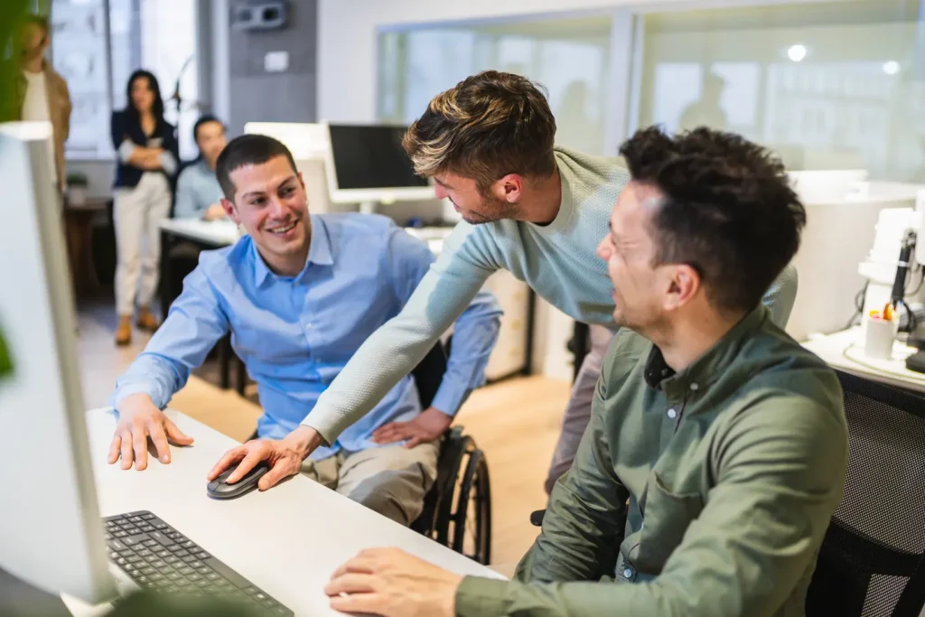 Group of young professional males in an office setting talking around a computer